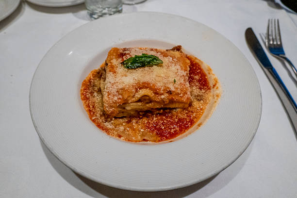 A delectable serving of classic Italian lasagna, layered with rich meat sauce, creamy béchamel, and melted cheese, topped with fresh herbs and a sprinkle of Parmesan, served in a vibrant tomato sauce