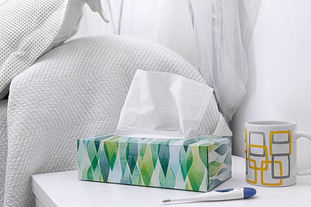 istock Box of tissues on a white table with a thermometer and a cup. 2239447497