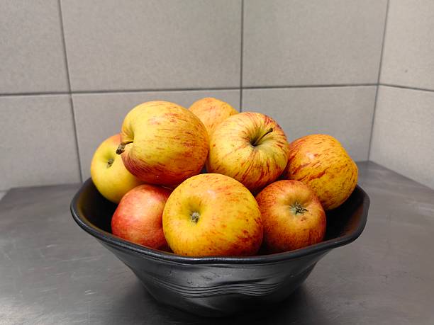 A bowl of fresh pink ripe apples on the table.