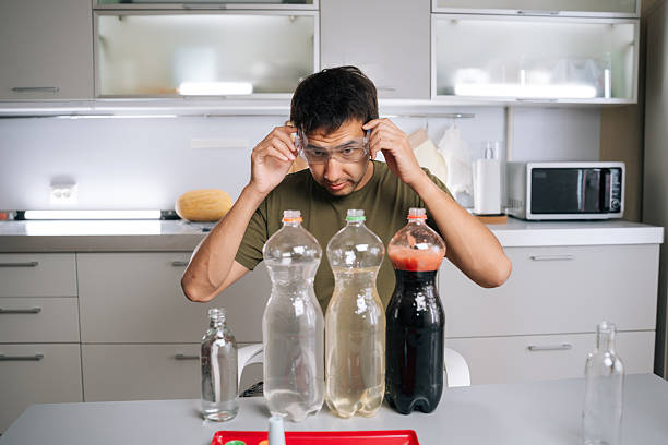 Chemist wearing safety glasses carefully preparing fertilizer for plants in kitchen, using various liquids and bottles, ensuring mixture safe and effective