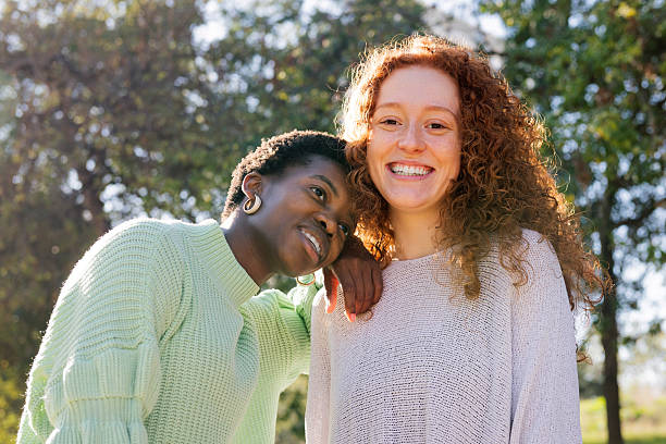 istock two young women smiling and hugging at park 2239454971