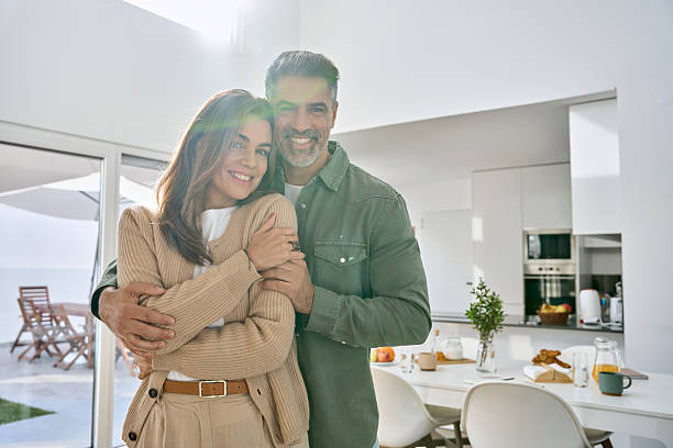 istock Happy mature couple hugging looking at camera standing in kitchen at home. 2239455390