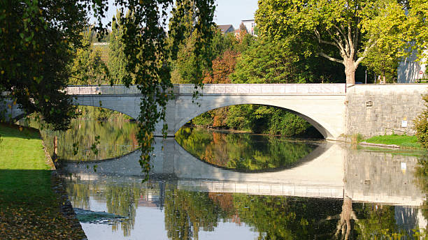 istock Beautiful bridge over a calm river reflecting colorful trees during a sunny autumn day 2239456032