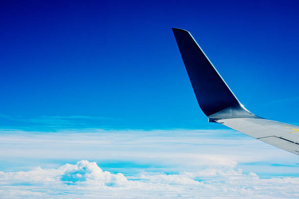 Airplane Wing and Blue Sky Above the Clouds