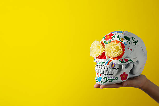 istock Mexican skull with flowers in hand on yellow background, space for text 2239477430