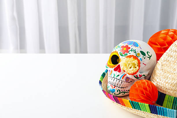 Mexican skull and paper balls in sombrero on light background, space for text