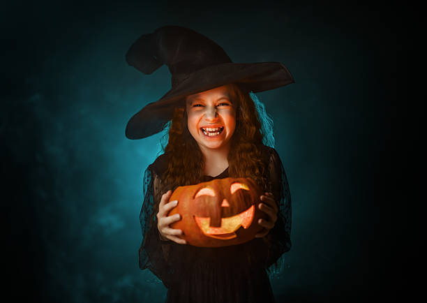 girl in witch costume with Halloween pumpkin