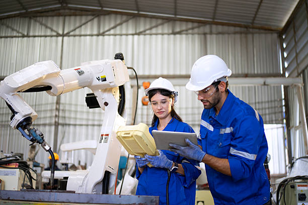 istock Blue collar workers at machine shop with welding robot arm. 2239480520