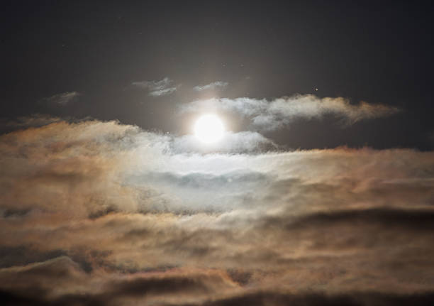 Cloudy sky with a bright sun in the middle. The sky is mostly dark with a few spots of light