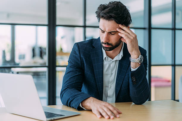 istock Stressed businessman having headache while working on laptop in the office. 2239489293