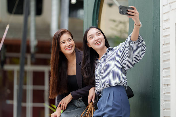 istock Two smiling young asian women taking selfie with mobile 2239489858