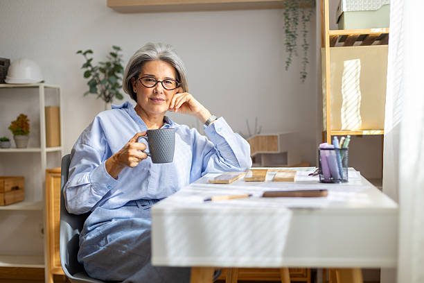 istock Senior woman architect relaxing with coffee in home office 2239490149
