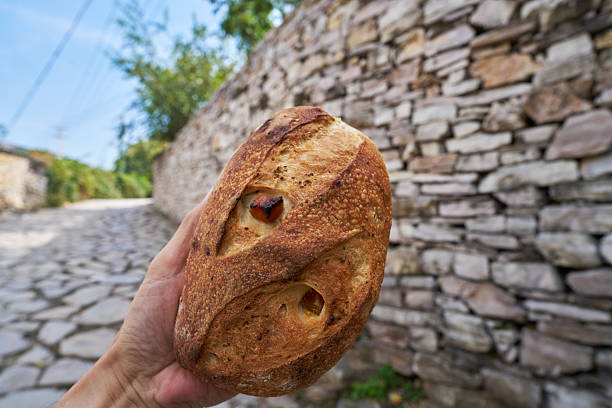hand holding a freshly baked sourdough artisan bread in a village