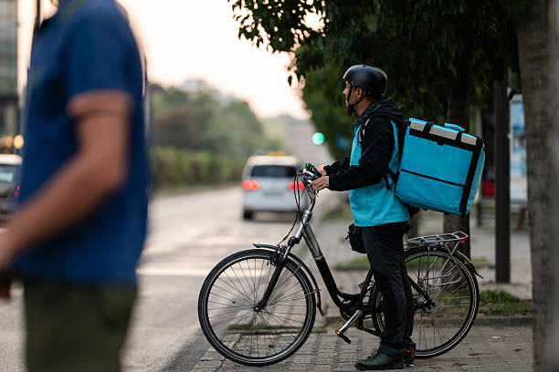 istock Deliveryman waiting at traffic light with bicycle and thermal backpack 2239497308
