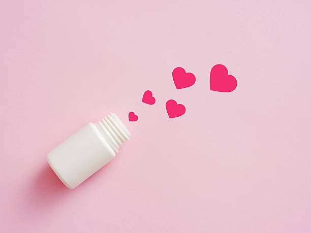 istock Medicine bottle dispensing red hearts on pink background 2239499741