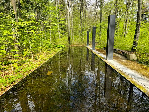 The forest cemetery was planned and built in 1913/14 by the then leading cemetery architect and Munich city planning officer Professor Hans Grässel in the Rheinhardwald forest in the Niklausen district of Schaffhausen. The image shows th eUrn burial site with water area Captured during spring season.