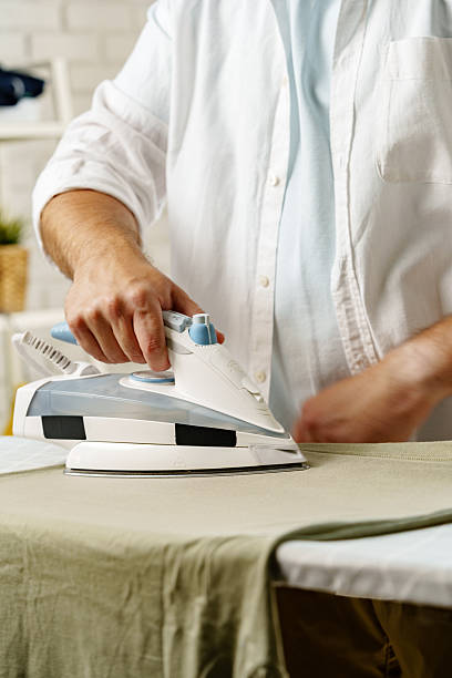 istock Man ironing a shirt at home during daylight hours for everyday chores 2239504529