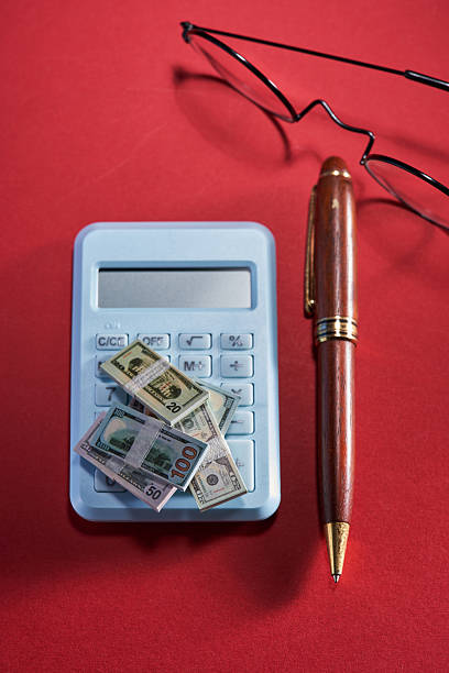 small dollar bill with a calculator in the background portraying declining purchasing power of a deflated dollar and the effects of inflation.