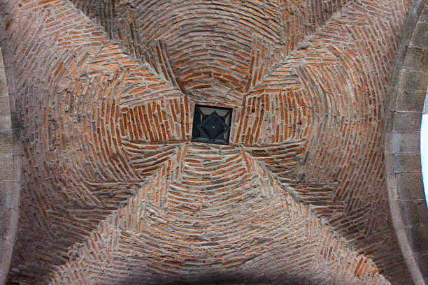Intricate Brickwork Pattern on Vaulted Ceiling - Close-up, low-angle view of an old architectural ceiling vault featuring a complex, swirling brick pattern.