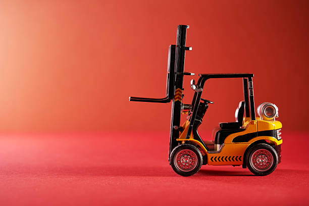 side view of toy tow forklift against red background.