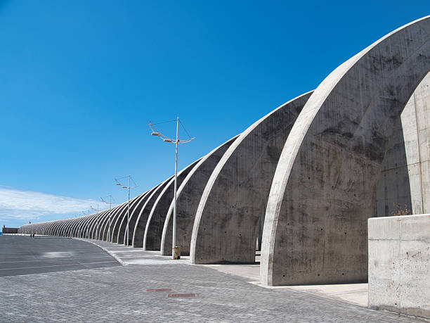 istock Contemporary Architectural Concrete Arches - Modern concrete structure of repeated curving arches under a bright blue sky, creating a rhythmic abstract architectural pattern. 2239509285