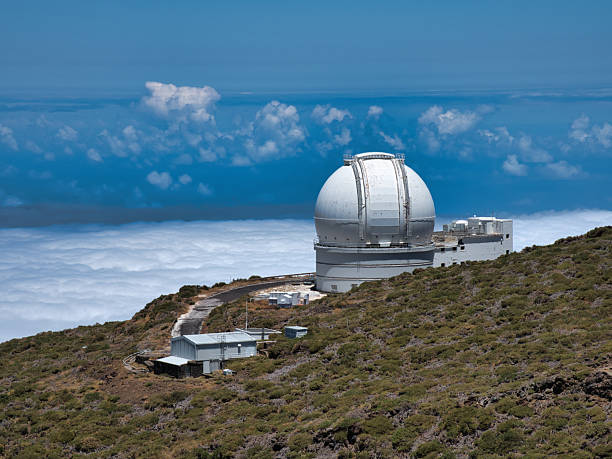 istock White Spherical Telescope Dome on Peak - Large white astronomical observatory with a spherical dome set high on a mountain ridge, overlooking clouds and the deep blue ocean. 2239509410