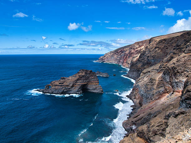 istock Atlantic Coastal Cliffs with Rock Arch - Dramatic high-angle view of rugged volcanic cliffs meeting the deep blue Atlantic Ocean, featuring a prominent natural rock arch formation. 2239509420