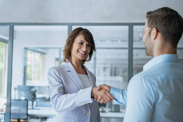 istock Two happy diverse partners, team professional business people shaking hands after successful work together. Mature Latin hispanic woman and young man doing handshake after signing contract in office 2239510052