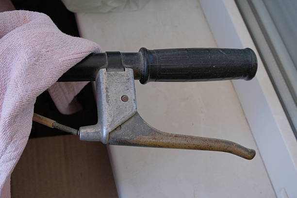 The handlebar of an old bicycle shows the brake handle panel on a light background next to the cape