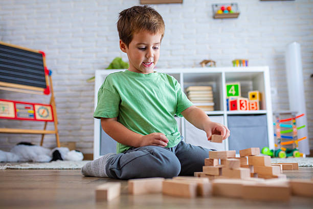 istock Kid Building Tower with Wooden Bricks on the Floor 2239511988