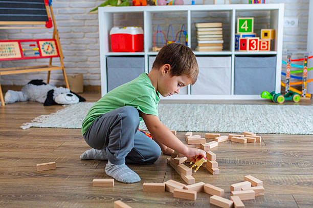 istock Kid Building Tower with Wooden Bricks on the Floor 2239512269