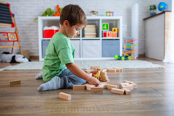 istock Kid Building Tower with Wooden Bricks on the Floor 2239512282