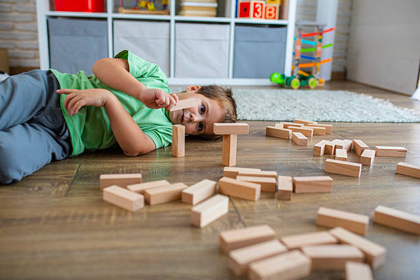 istock Preschool boy developing creativity and motor skills while lying on the ground and playing with blocks 2239512324