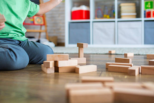 istock Kid Building Tower with Wooden Bricks on the Floor 2239512948