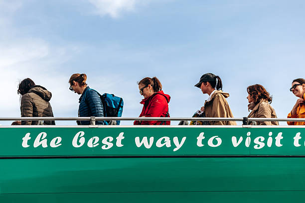 Gozo, Malta  April 12, 2025: Tourists disembark from a green open-top sightseeing bus under a blue sky, illustrating popular guided tours and public transport on Gozo island.