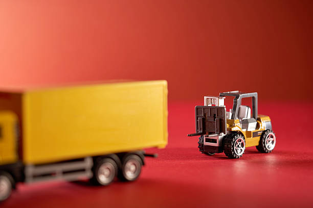 istock small toy forklift and cargo container against red background. 2239513105