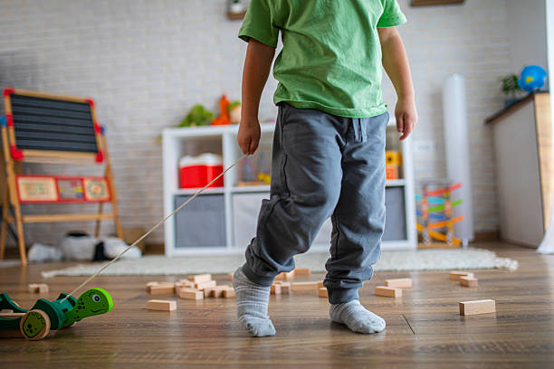 Boy engaged in imaginative play with a pull-along wooden toy surrounded by building blocks