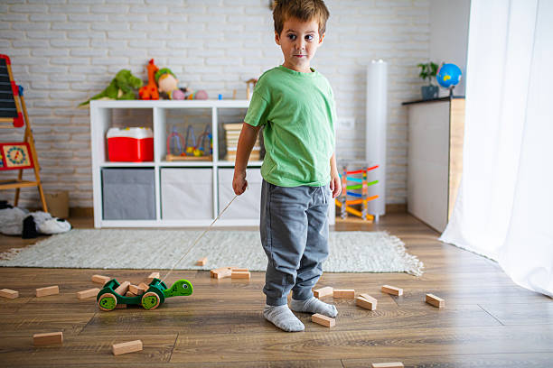 Boy engaged in imaginative play with a pull-along wooden toy surrounded by building blocks