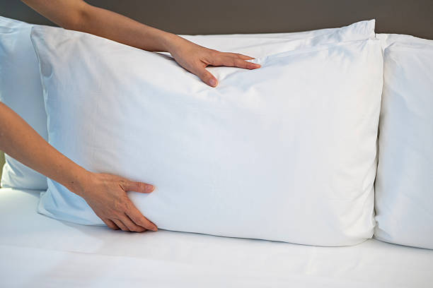 istock Adjusting clean white pillow on neatly made bed 2239513336