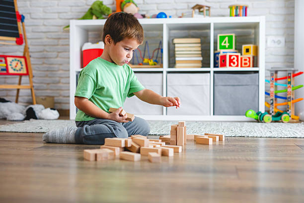 istock Kid Building Tower with Wooden Bricks on the Floor 2239513349
