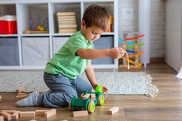 istock Boy engaged in imaginative play with a pull-along wooden toy surrounded by building blocks 2239513617