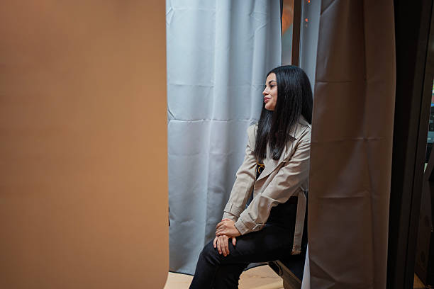 Young woman smiling while sitting inside a photo booth, creating memories