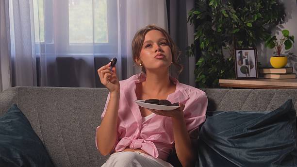 Young Woman Enjoying Cookies On Comfortable Sofa Afternoon