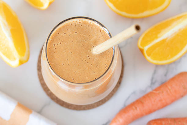 istock Orange and carrot smoothie in a glass on white marble table 2239517773