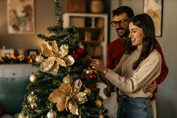 istock Young couple decorating christmas tree for holiday celebration 2239518025