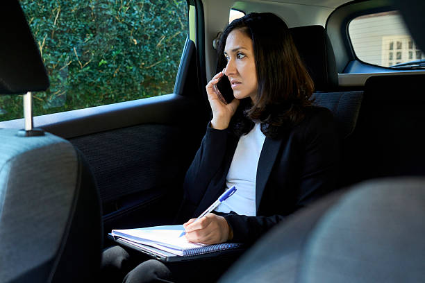 istock Businesswoman talking on phone and taking notes in car 2239521231