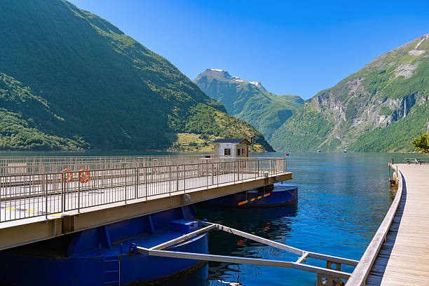 Geiranger ferry dock in  Geirangerfjord Norway UNESCO site, Fjord blue water, mountains and dock under clear summer sky