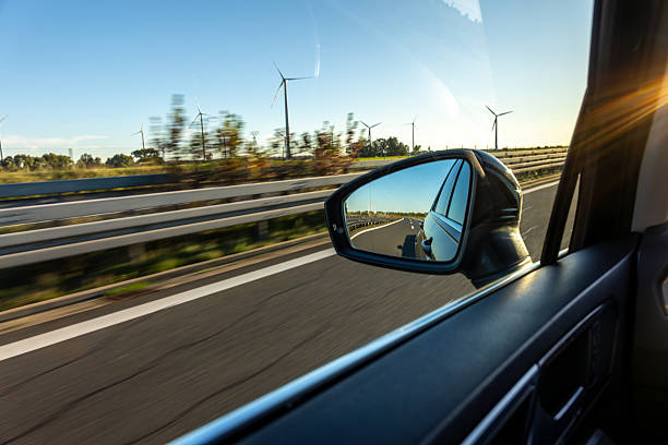 istock Car mirror with wind turbines view. Eco style journey. 2239522608