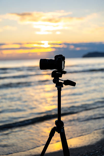 istock Camera on tripod by the sea at sunset. Tripod camera at beach. 2239522613