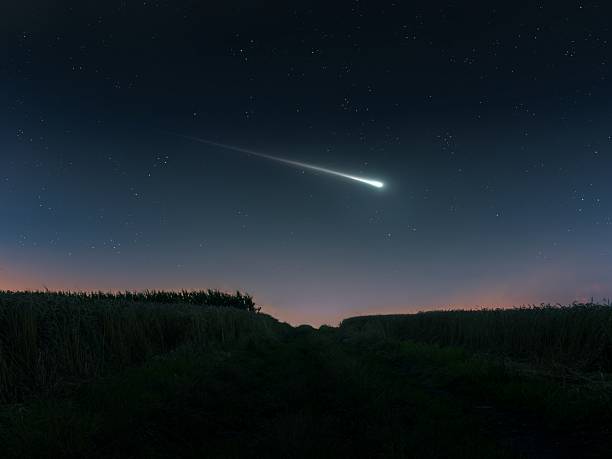Fireball in the evening sky over the fields. Bright shooting star. Meteor illuminates the starry sky.